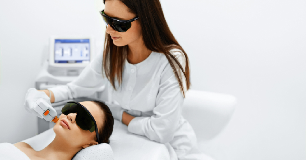 Blog 11 A skincare specialist performing a photofacial treatment on a female client using IPL (Intense Pulsed Light) technology. Both are wearing protective eyewear in a clinical setting in BOZEMAN, MT